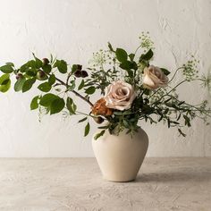 a white vase filled with flowers on top of a table