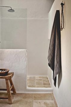 a white bathroom with a wooden stool and shower