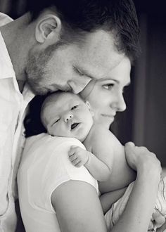 a man and woman holding a baby in their arms