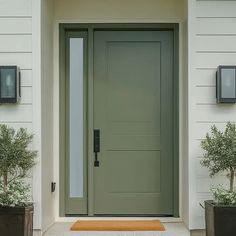 a green front door with two planters on either side and three lights above it