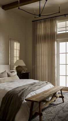 a bed sitting in a bedroom next to a window with curtains on the windowsill