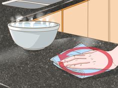 a person washing dishes in the kitchen with a cloth on the counter top and a bowl next to it