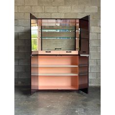 an empty display case in front of a brick wall with shelves and glass doors on it