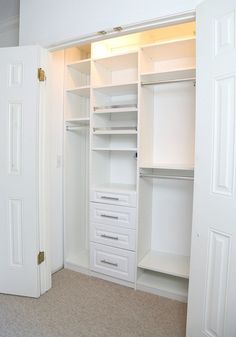 an empty closet with white shelves and drawers