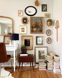 a room filled with lots of framed pictures on the wall next to a desk and chair