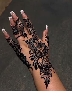 a woman's hand with black henna on it and white nails in the middle