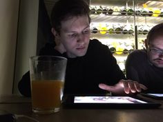 two men sitting at a table in front of a tablet computer and a glass of orange juice