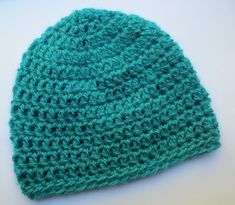 a green crocheted hat sitting on top of a table