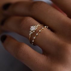 a woman's hand with two gold rings on her fingers and one diamond ring in the middle