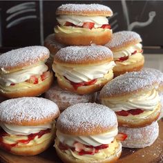 a pile of doughnuts sitting on top of a wooden tray covered in powdered sugar