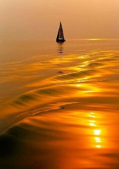 a sailboat in the ocean at sunset with waves coming up on it's sides