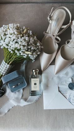 a bouquet of flowers, shoes and perfume on a couch next to some wedding accessories