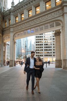 a man and woman are walking under an archway