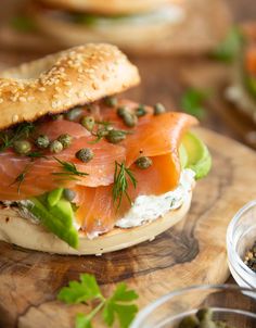 a bagel sandwich with salmon and capers on it sitting on a cutting board