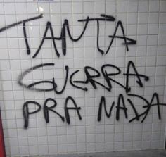 graffiti written in spanish on the wall of a public bathroom stall with urinals