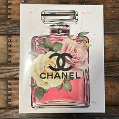 a chanel perfume bottle with a rose on the front and back cover, sitting on top of a wooden table