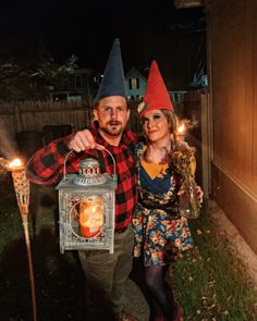 a man and woman dressed up as gnomes holding a lantern with candles in it