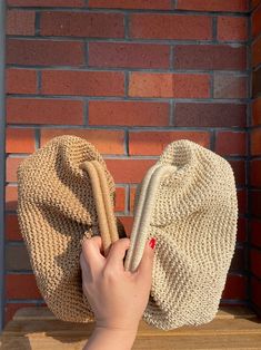 a woman's hand holding onto a straw hat on top of a wooden table