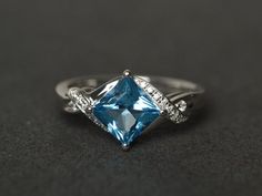 Welcome to my shop, you can find many beautiful gemstone jewelry here, and you also can ask for customized service. Main Stone: Swiss blue topaz, square cut 7X7mm,  about 2.30 carats Accent Stones: cz Metal: 925 sterling silver plated with rhodium. I also can provide metal options such as 14k solid yellow/white/rose goldSetting: prong setting More rings: https://www.etsy.com/shop/XCjewelryStudio?ref=hdr_shop_menuIt's a perfect gift for the person who was born in November (Birthstone), it's quite Fine Jewelry Princess Cut Topaz Promise Ring, Princess Cut Topaz Ring With Center Stone For Promise, Princess Cut Blue Topaz Ring For Promise, Fine Jewelry Topaz Ring With Princess Cut, Blue Topaz Princess Cut Ring For Promise, Blue Topaz Princess Cut Promise Ring, Fine Jewelry Princess Cut Topaz Ring, Princess Cut Blue Topaz Promise Ring, Square Cut Topaz Ring For Wedding