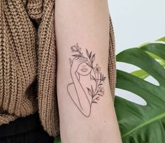 a woman's arm with a tattoo on it and a plant in the middle