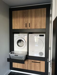 a washer and dryer in a room with wooden cabinets on the wall behind them