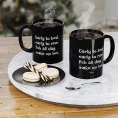 two black coffee mugs sitting on top of a white plate next to each other