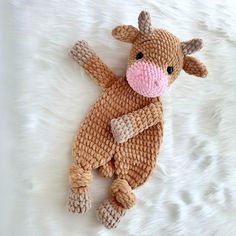 a stuffed cow laying on top of a white blanket