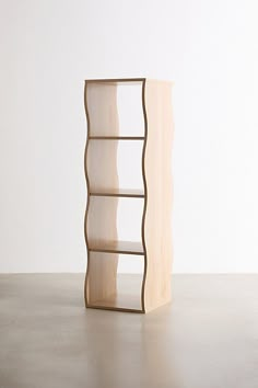 a wooden shelf sitting on top of a floor next to a white wall with a vase in it