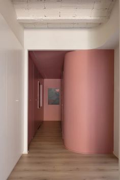 an empty room with pink walls and wooden floors is seen in this image from the hallway