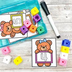 two bears and letters are on the table next to some plastic blocks with colored rubber cubes