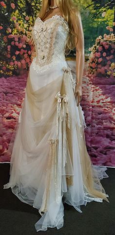 a mannequin dressed in a wedding dress with flowers on the wall behind it