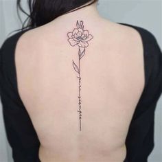 the back of a woman's neck with a flower tattoo on it