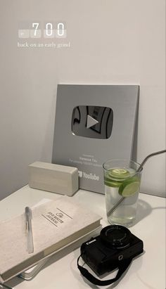 a table with a camera, notebook and pen on it next to an empty book