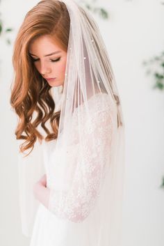 a woman wearing a wedding veil with flowers in the background