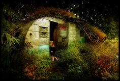 a woman is standing in the doorway of an abandoned building surrounded by plants and trees