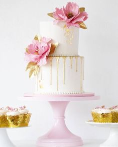 a white and gold cake with pink flowers on top