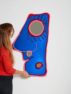 a woman holding up a blue and red piece of art