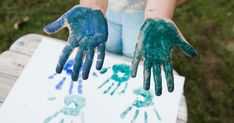 two children's hands painted with blue and green paint sitting on top of a table