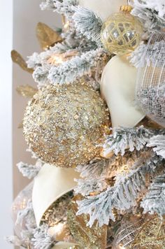 a white and gold christmas tree with ornaments