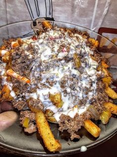 a large bowl filled with food sitting on top of a table next to a person's hand