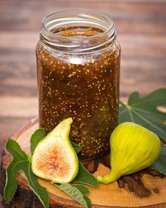 figs and honey in a jar sitting on a wooden slice with leaves around it