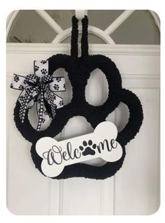 a black and white door hanger that says welcome with a dog bone on it