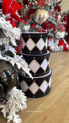 three stacked black and white boxes next to a christmas tree