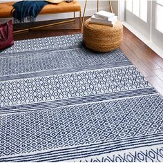 a blue and white area rug on the floor in front of a window with a bench