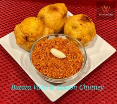 some food is on a white plate with red table cloth and the words batata vada & lesson chutey