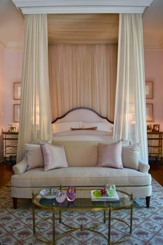 a canopy bed sitting in the middle of a living room next to a coffee table