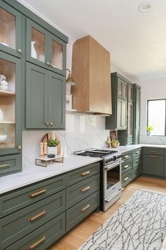 a kitchen with green cabinets and white counter tops, an area rug on the floor