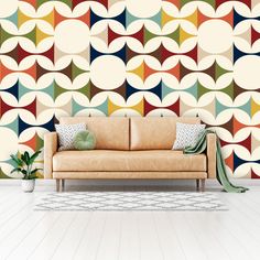 a couch sitting in front of a colorful wallpaper with circles on it's walls