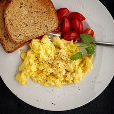 an egg salad on a plate with toast and cherry tomatoes next to it is ready to be eaten