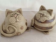 two ceramic cat figurines sitting next to each other on a white tablecloth